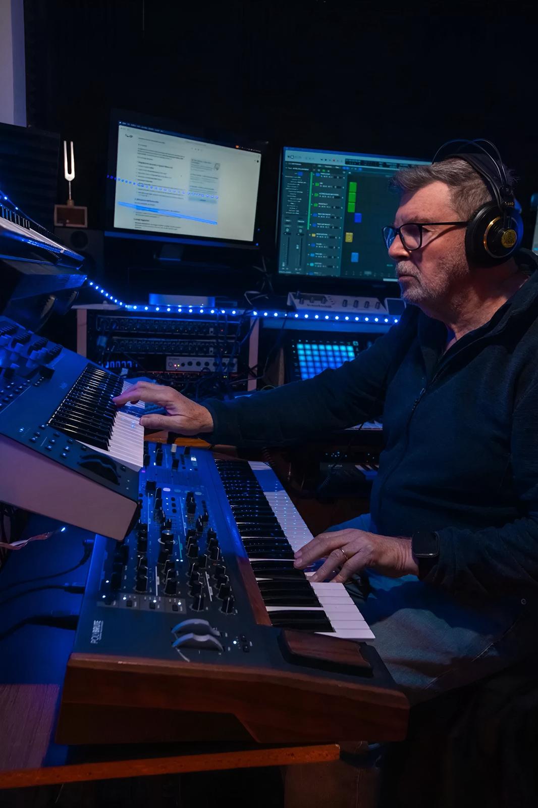 Music producer using synthesizers and digital audio workstation in a home studio