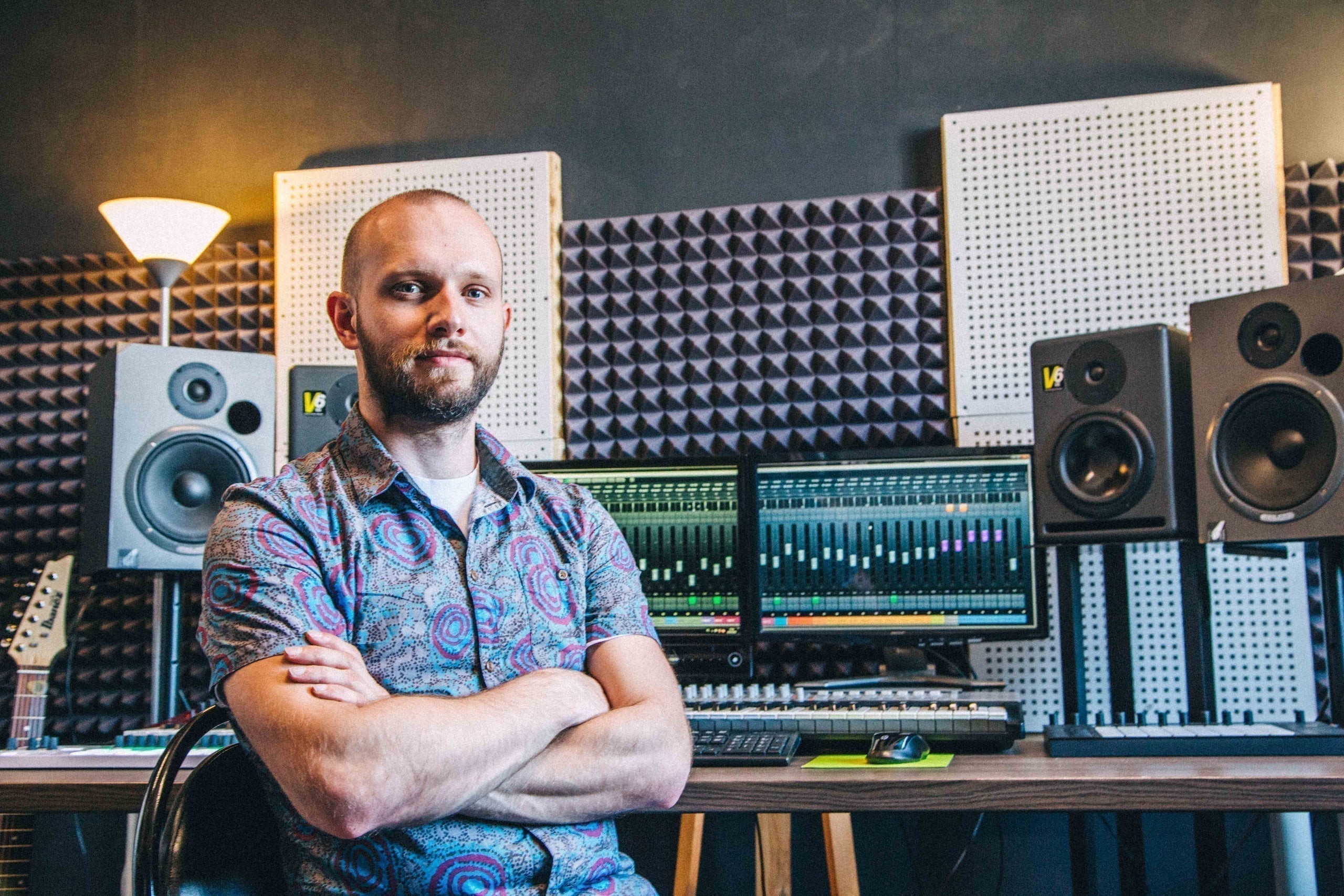 Music producer in a recording studio with monitors, acoustic panels, and mixing equipment